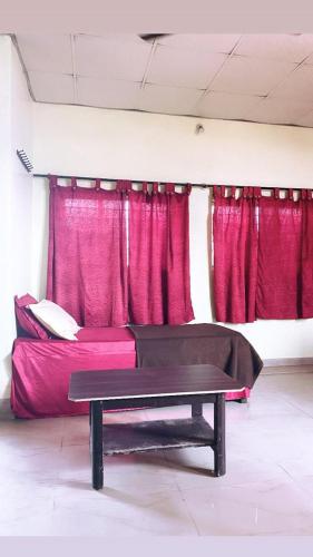 um quarto com uma cama com cortinas vermelhas e uma mesa em Empire lodge em Chikmagalur
