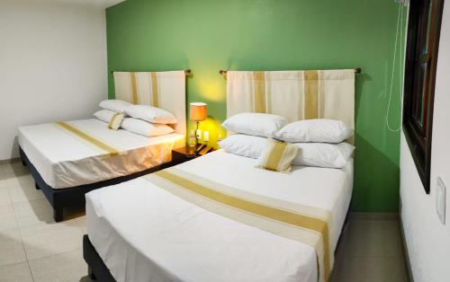 2 letti in una camera con pareti verdi di Nueve Agaves Hotel a Tequila