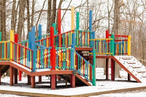 um parque infantil com equipamento colorido na neve em Carriage House Country Club em Pocono Manor