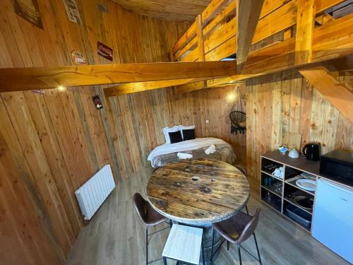 Cette chambre en bois comprend une table et un lit. dans l'établissement La Cabane Tonneau - Les Pieds dans le Pré, à Les Landes-Génusson