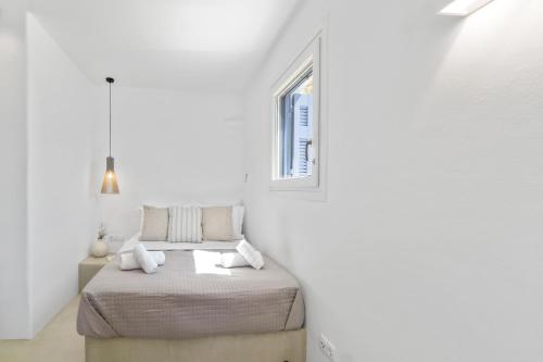 a white room with a bed and a window at Villa Gaia, Beachfront, Plunge Pool & Sunset by Explore Andros in Apróvaton