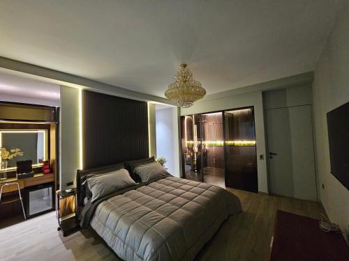 sypialnia z łóżkiem, biurkiem i żyrandolem w obiekcie Blloku Suites, City Centre,Tirana w Tiranie