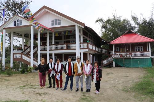 un grupo de personas parados frente a una casa en Tsering's Homestay Oyan, en Pāsighāt