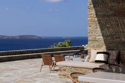 a patio with chairs and tables and a view of the ocean at Villa Gaia, Beachfront, Plunge Pool & Sunset by Explore Andros in Apróvaton