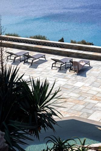a group of picnic tables on a patio overlooking the ocean at Villa Gaia, Beachfront, Plunge Pool & Sunset by Explore Andros in Apróvaton