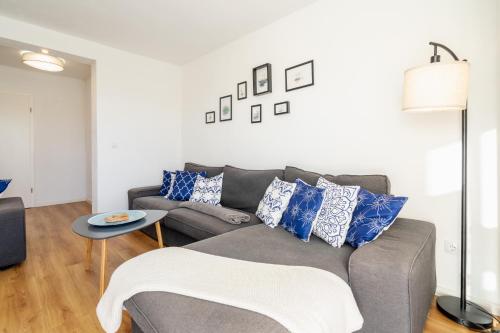 a living room with a gray couch and blue pillows at Strand Familien Doppelhaushälfte ,,MARSI'' #Familien-Urlaub in Rappin