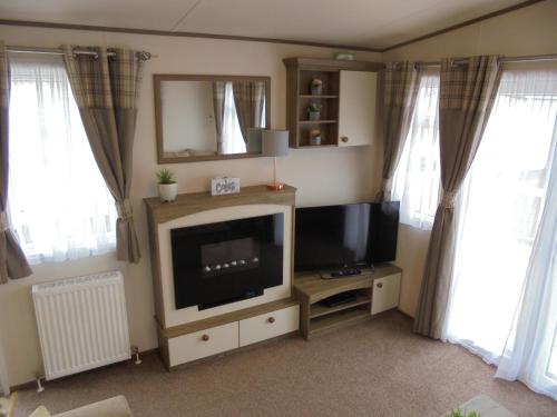 a living room with a flat screen tv and two windows at The Grange Ingoldmells: Elan 6 berth, Central Heated, Wrap Around Decking in Ingoldmells