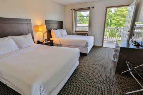 a hotel room with two beds and a balcony at Nader's Motel & Suites in Ludington