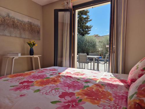 - une chambre avec un lit avec une couette à fleurs et une porte coulissante en verre dans l'établissement Villa avec piscine dans un domaine viticole, à Domazan
