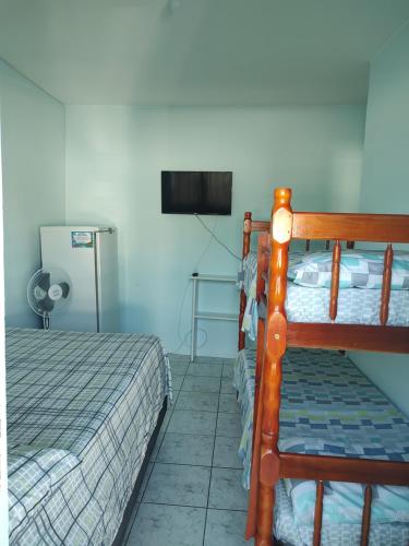 a bedroom with a bunk bed and a flat screen tv at Pousada Golfinhos in Imbé