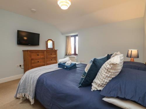 a bedroom with a blue bed with a tv on the wall at Little Tregarrick in Helston