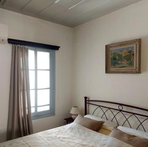 a bedroom with a bed and a window at Danaë Port House in Hydra