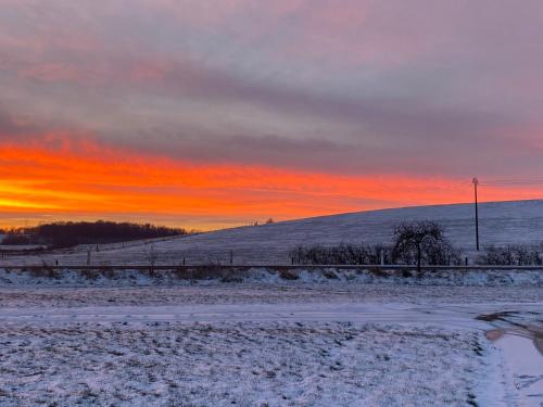a snowy field with a sunset in the background at Gîtes Marie Rose - PMR in Spincourt