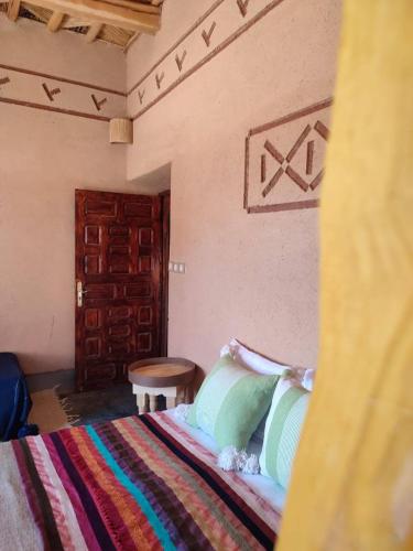 a bedroom with a bed and a wooden door at Maison d'hôtes IZZA in Kalaat MGouna