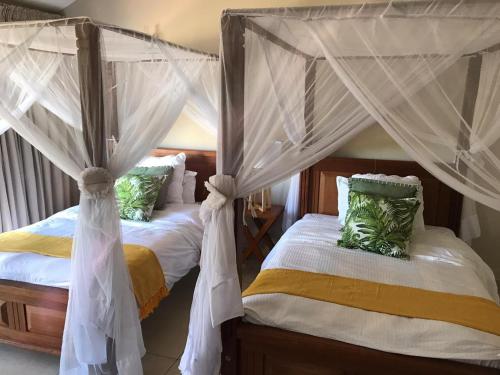 two beds with mosquito nets in a bedroom at A80@VIPINGO RIDGE in Kilifi