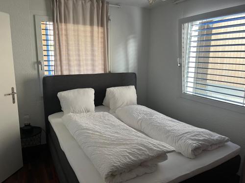 Bett mit weißen Decken und Kissen in einem Zimmer in der Unterkunft Schöne Doppelzimmer in Mandach in Böttstein