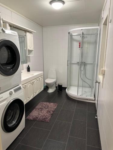 a bathroom with a washing machine and a shower at Vardø accommodation - white house in Vardø