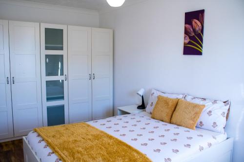 a bedroom with white cabinets and a bed with a yellow blanket at Charming 2-Bed Fully Furnished Apartment in London in London