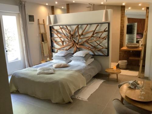 ein Schlafzimmer mit einem großen Bett mit einem hölzernen Kopfteil in der Unterkunft Le carpe noctem suite de charme avec jacuzzi privé in Sérignan-du-Comtat