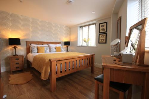 1 dormitorio con cama, escritorio y espejo en Streamside Apartments, en Yeovil