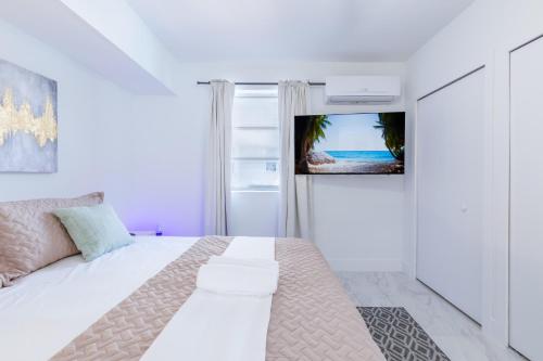 een witte slaapkamer met een bed en een tv aan de muur bij King-Size Bed, Parking Free Near Brickell & Grove in Miami