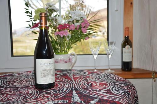 dos botellas de vino sentadas en una mesa con copas en Glas Bheinn Cottage en Luib