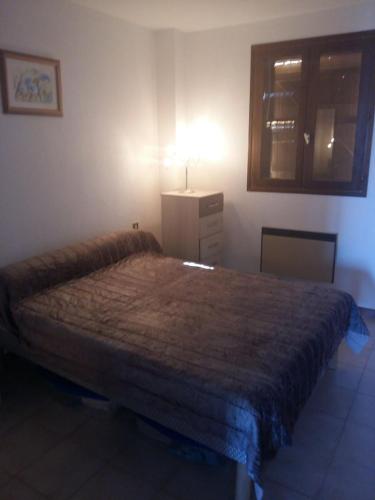 - une chambre avec un grand lit et un couvre-lit marron dans l'établissement Appartement avec piscine partagée, à Calenzana