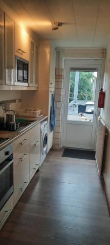 uma cozinha com uma máquina de lavar roupa e uma porta para um quintal em SIMLA INDIAAS RESTAURANT VOOR KAMER em Sittard