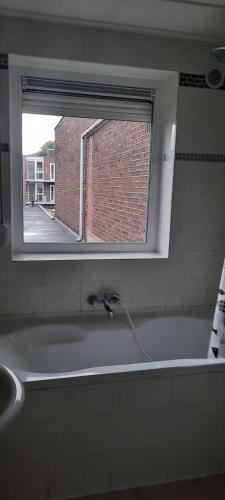 a bathroom with a bath tub with a window at SIMLA INDIAAS RESTAURANT VOOR KAMER in Sittard