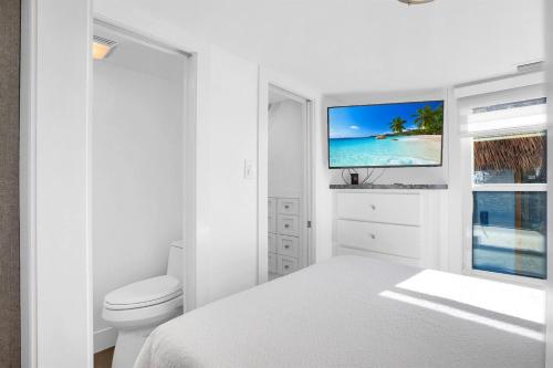 Jewfish的住宿－Tiny Home on Waterfront, Bay Views, Deck, Pool，白色卧室设有一张床和墙上的电视