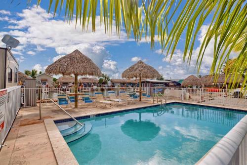 a swimming pool with straw umbrellas and lounge chairs at Tiny Home on Waterfront, Bay Views, Deck, Pool in Jewfish
