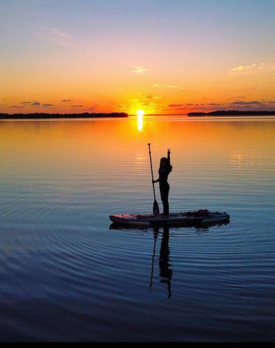 a person standing on a paddle board in the water at sunset at Tiny Home on Waterfront, Bay Views, Deck, Pool in Jewfish
