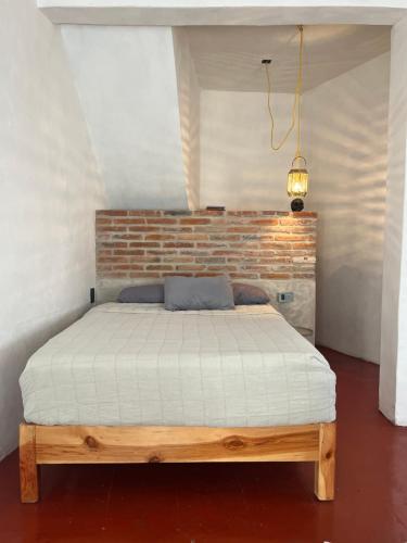 a bed in a room with a brick wall at Casa Roma in Taxco de Alarcón