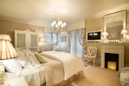 a bedroom with a white bed and a fireplace at Casa Regaleira Hotel Boutique in Campos do Jordão