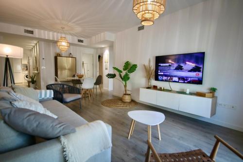 a living room with a couch and a tv on a wall at Aguacate Beach Apartamentos Playa Granada in Motril
