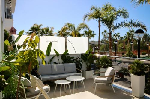 a patio with a couch and chairs and palm trees at Aguacate Beach Apartamentos Playa Granada in Motril