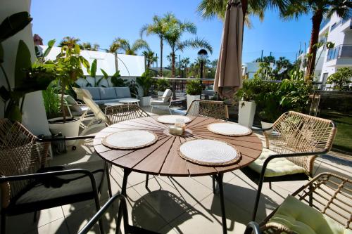 a wooden table on a patio with chairs and an umbrella at Aguacate Beach Apartamentos Playa Granada in Motril