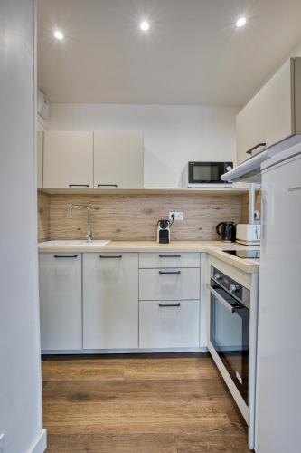 une cuisine avec des armoires blanches et un évier dans l'établissement App Le Galet 5min du port, à Fécamp