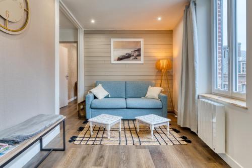 ein Wohnzimmer mit einem blauen Sofa und einem Fenster in der Unterkunft App Le Galet 5min du port in Fécamp