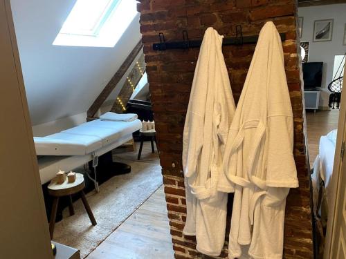 une chambre avec des serviettes suspendues sur un mur en briques dans l'établissement Loft Romantique - Balnéo - Billard - Massage, à Verton