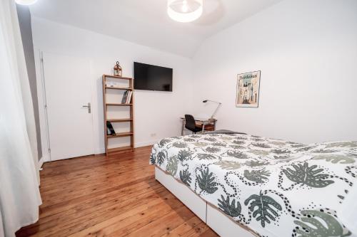 1 dormitorio con 1 cama y TV en la pared en Le Domaine du petit Basque en Talence