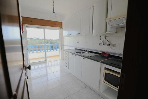 a kitchen with white cabinets and a large window at cantinho do mar in Albufeira