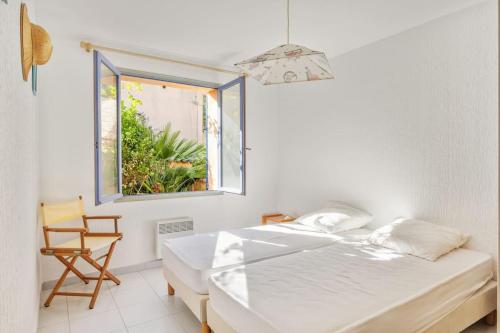 1 dormitorio con 1 cama, 1 silla y 1 ventana en Villa Piscine, vue mer Cap Nègre, en Le Lavandou