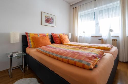 a bedroom with a bed with orange pillows and a window at Appartementhaus Elfi in Barnbäch