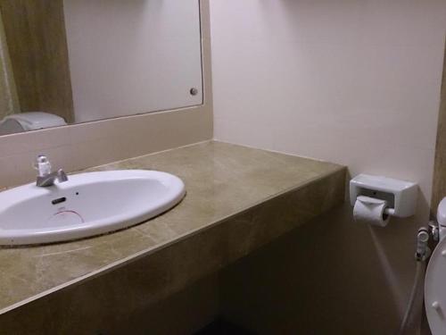 a bathroom with a sink and a mirror and a toilet at The Blooms Residence in Bangkok