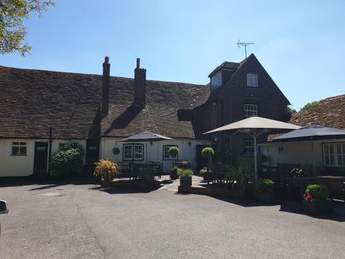 a large house with a courtyard with tables and umbrellas at Ye Olde George Inn - Badger Pubs in Privett