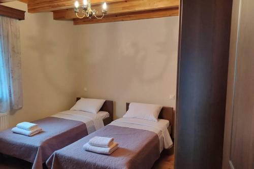 two beds in a room with towels on them at Agnes Cottage House in Konitsa