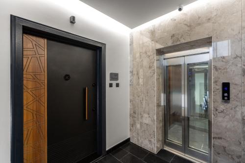 a hallway with a black door and stone walls at شقة غرفتين وصالة ومطبخ in Medina