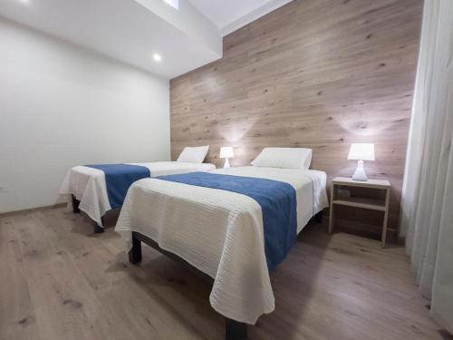 2 Betten in einem Zimmer mit Holzwänden in der Unterkunft Hotel Casa costa in Mollendo