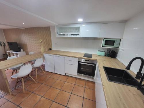 Una cocina con gabinetes blancos y una encimera de madera. en Apartamento El Olivo, en Vigo